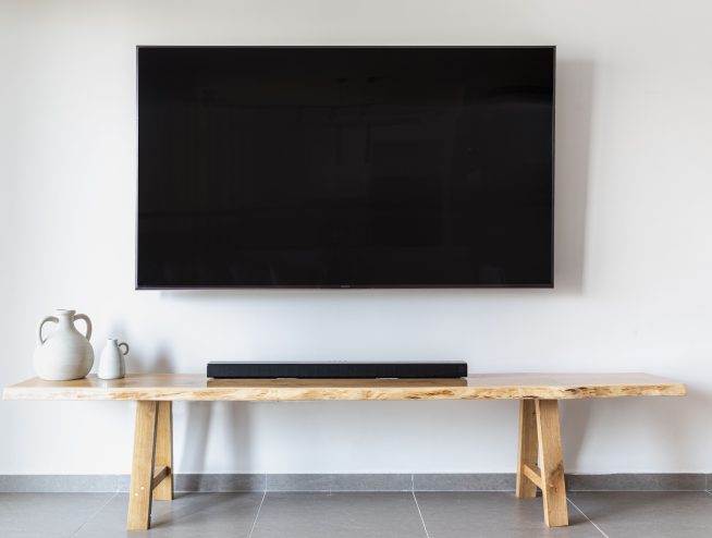 A flat screen tv mounted on wall over a wooden console